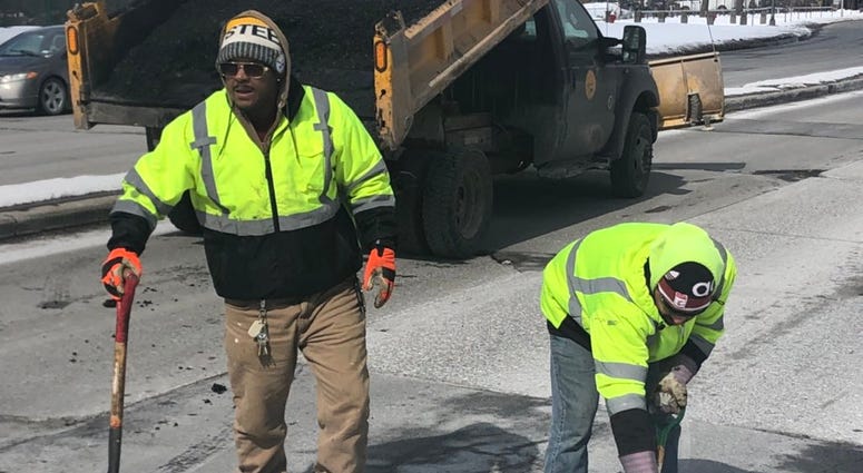 Two workers filling potholes on Busti Avenue on Wednesday