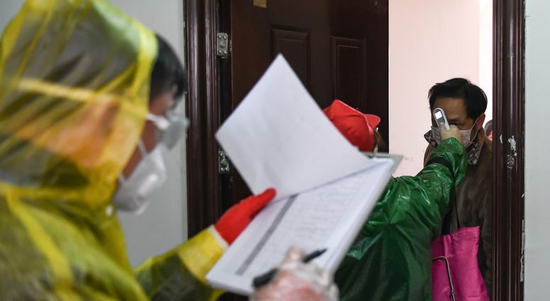 A resident takes body temperature check during a health screening campaign at Qingheju Community