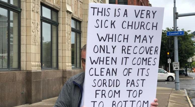 Protester with sign outside Diocese of Buffalo. September 10, 2018 (WBEN Photo/Mike Baggerman)