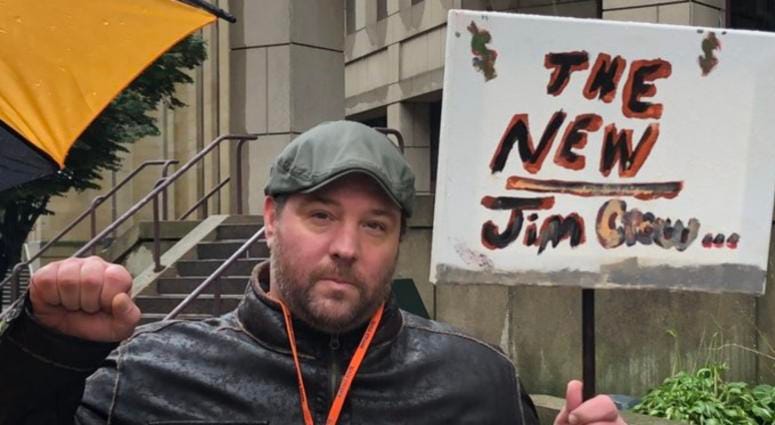 Protester Michael Mottern is calling for the removal of Sheriff Tim Howard outside the Holding Center.