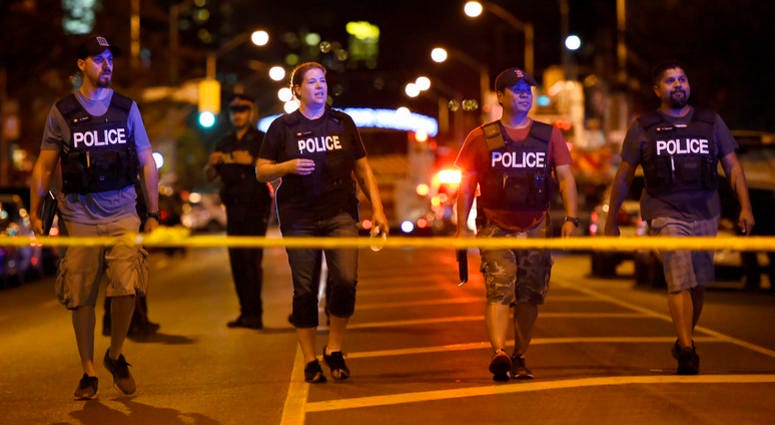 Plainclothes police officers work the scene of a shooting in Toronto on Sunday, July 22, 2018.