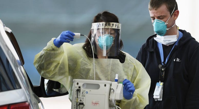 Medical staffers at UNC Hospitals in Chapel Hill, N.C., screen a patient at a drive-thru COVID-19 screening site outside the emergency department.