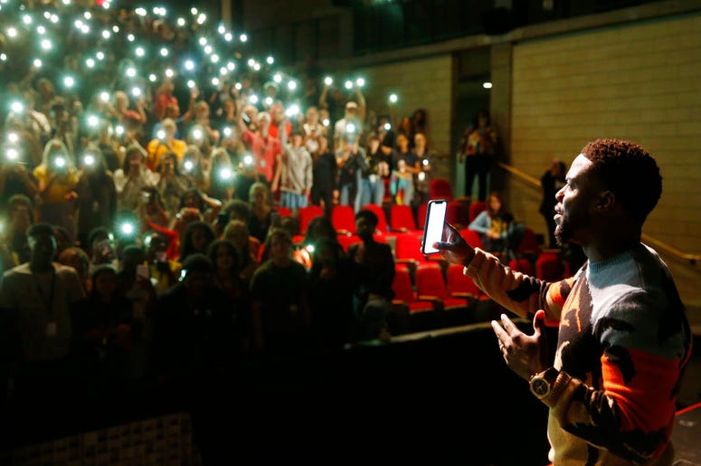 In this Sept. 12, 2018 photo, comedian and actor Kevin Hart films himself from a cellphone after talking to the students at Booker T. Washington High School in Dallas. DO NOT USE