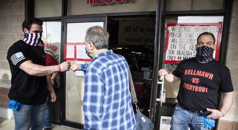 Atilis Gym co-owners Ian Smith, left, and Frank Trumbetti welcome a customer to their gym in Bellmawr, N.J., Tuesday, May 19, 2020. Atilis Gym (AP)