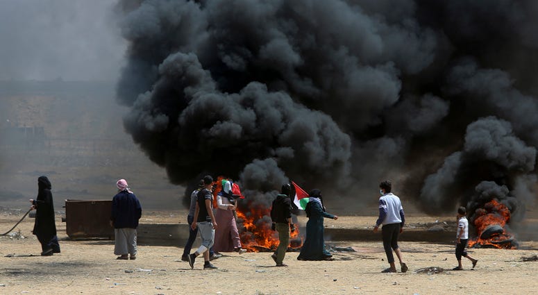 Palestinian protesters burn tires near the Israeli border fence, east of Khan Younis, in the Gaza Strip, Monday, May 14, 2018. Gaza Protests