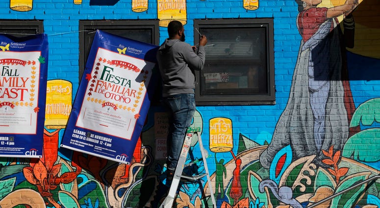A building supervisor, who declined to identify himself, hangs banners on the front of the Jacob Riis Settlement House, Friday, Nov. 16, 2018, in New York. Amazon LIC Headquarters