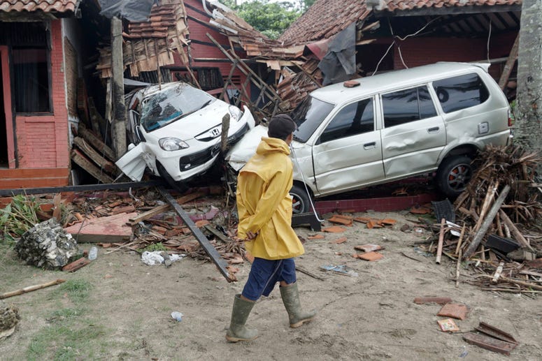 A villager walks past a car damaged by a tsunami, in Carita, Indonesia, Sunday, Dec. 23, 2018. Indonesia Tsunami