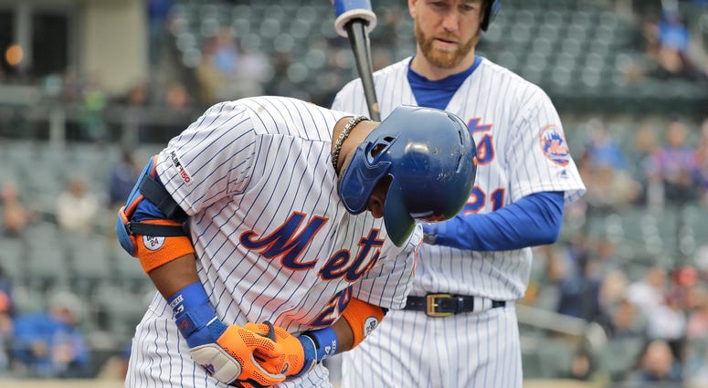 New York Mets' Robinson Cano, left, reacts after being hit by a pitch during the first inning of the MLB baseball game against the Milwaukee Brewers at Citi Field, Sunday, April 28, 2019, in New York. Robinson Cano