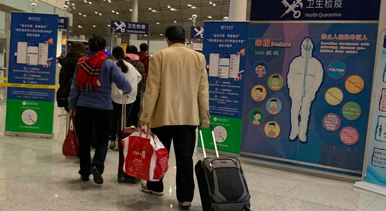 In this Jan. 13, 2020, photo, travelers pass by a health checkpoint before entering immigration at the international airport in Beijing. JFK China screening