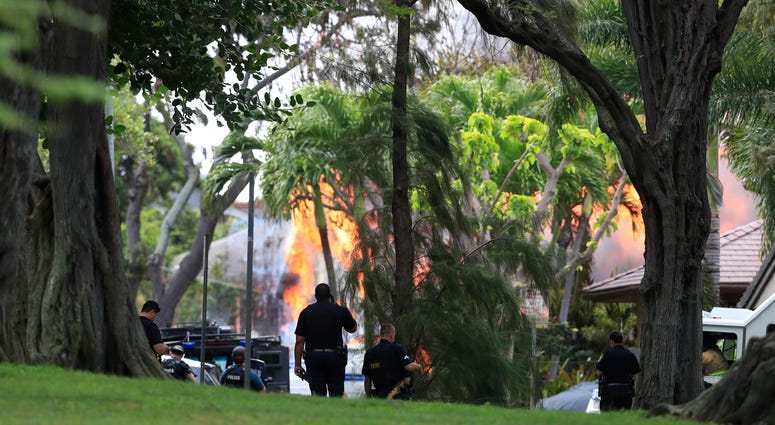 Honolulu police watch a house fire after a shooting and domestic incident at a residence on Hibiscus Road near Diamond Head on Sunday, Jan. 19, 2020, in Honolulu. Honolulu shooting