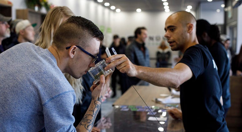 Kyle Bell, of Numo Cannabis, helps a customer decide on his purchase of legal marijuana in Edmonton, Alberta, Wednesday, Oct. 17, 2018. Canada became the largest country with a legal national marijuana marketplace as sales began early Wednesday. Canada Marijuana Legalization