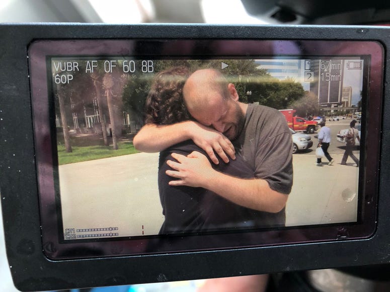 Men hug outside Jacksonville Landing.