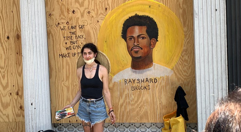 An artist beside her artwork. Plywood SoHo