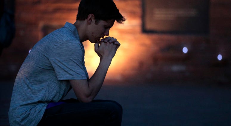 Spencer Greenlee, 17, a senior at Columbine High School prays at the Columbine Memorial during a candle light vigil held on April 19, 2019 in Littleton, Colorado. Columbine anniversary