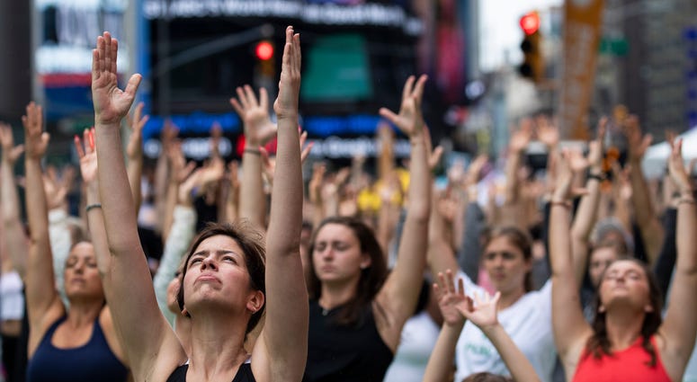 oga enthusiasts participate in a mass yoga class in Manhattan's Times Square to celebrate the summer solstice and mark World Yoga Day, June 21, 2019 in New York City. Yoga Times Square