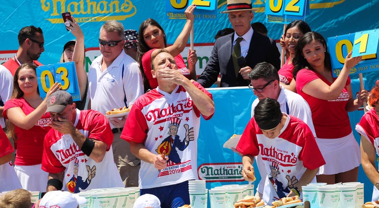 Joey Chestnut (C) eats during the men's hot dog eating contest on July 4, 2019 in New York City. Nathan's Hot Dog Eating Contest