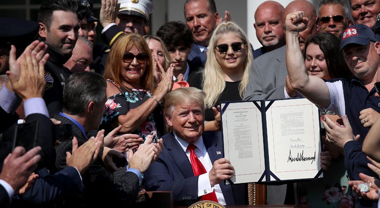 Surrounded by first responders and their families, U.S. President Donald Trump signs H.R. 1327, an act to permanently authorize the September 11th victim compensation fund, in the Rose Garden of the White House July 29, 2019 in Washington, DC. President Trump Signs September 11th Victim Compensation Fund Act