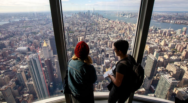 Visitors look toward Lower Manhattan inside the newly renovated 102nd floor observatory of the Empire State Building on October 10, 2019. Empire State Building Observatory