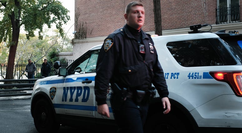 An NYPD officer walks by an NYPD SUV. NYPD officer