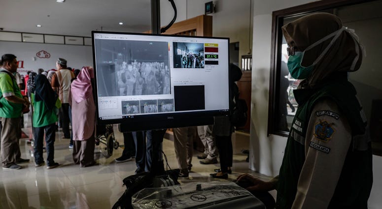 An Indonesian health official monitors as passengers from an international flight have their temperature checked as they pass a thermal scanner monitor upon arrival at the Adisucipto International Airport on January 23, 2020 in Yogyakarta, Indonesia. Coronavirus Screening
