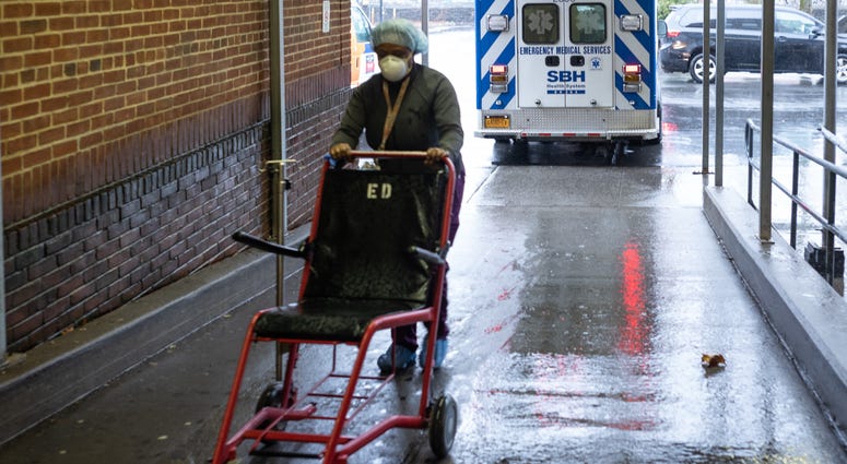 A staff member pushes a wheelchair at St. Barnabas Hospital on March 23, 2020 in the Bronx borough of New York City. Coronavirus NYC