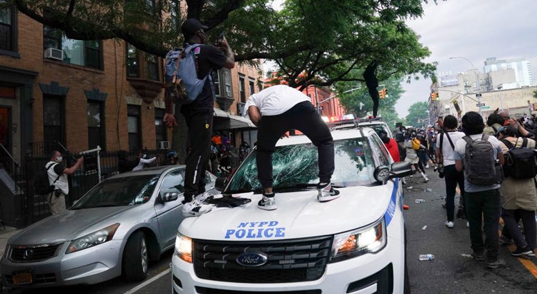 Protesters jump on an NYPD police SUV during a demonstration against the killing of George Floyd by Minneapolis police on Memorial Day on May 30, 2020 in the Borough of Brooklyn in New York. George Floyd Protest In New York