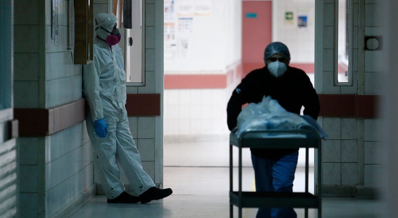Health worker rests as a team member carries supplies during the coronavirus pandemic at San Jose Hospital on June 16, 2020 in Santiago, Chile. Coronavirus