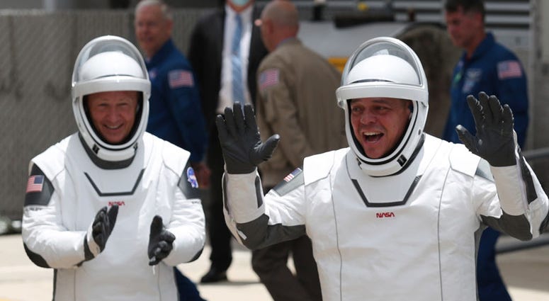 NASA astronauts Bob Behnken (R) and Doug Hurley (L) walk out of the Operations and Checkout Building on their way to the SpaceX Falcon 9 rocket with the Crew Dragon spacecraft on launch pad 39A at the Kennedy Space Center on May 27, 2020 in Cape Canaveral Bob Behnken and Doug Hurley