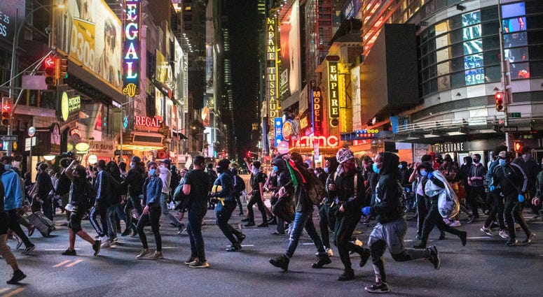 Protesters rush past Times Square after an 11pm curfew during a night of marches and vandalism over the death of George Floyd on June 1, 2020 in New York City. Curfew New York City