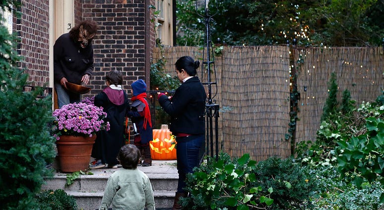 An adult dressed as a werewolf gives candy to young children who are "trick or treating" as Brooklyn residents participate in Halloween activities on October 31, 2012 in New York City. Trick or Treating