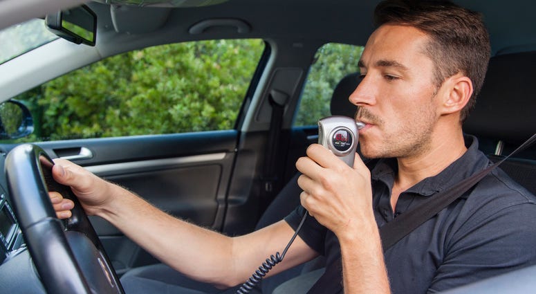 Man in car blowing into breathalyzer Ignition Interlock System
