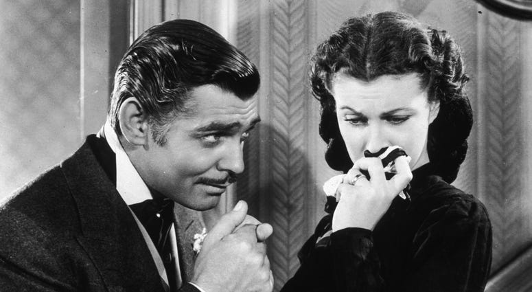 American actor Clark Gable (1901 - 1960) in his role as Rhett Butler kissing the hand of a tearful Scarlett O'Hara, played by Vivien Leigh in 'Gone With The Wind'. Gone with the Wind