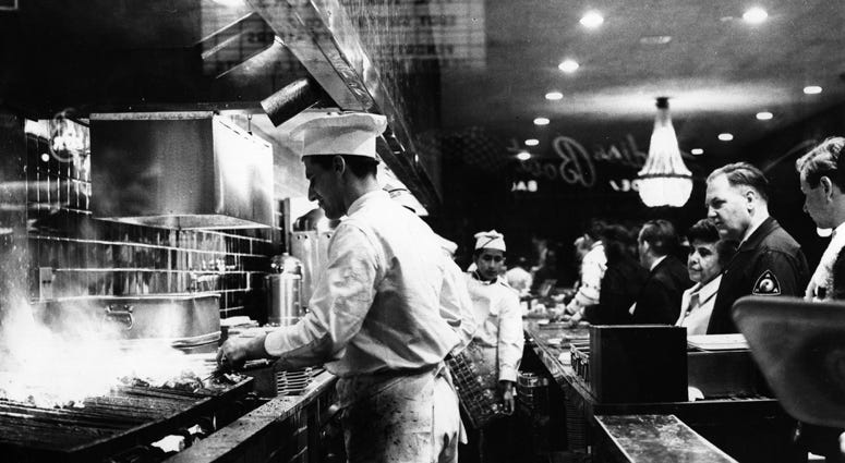 As customers queue up, cooks broil steaks on the charcoal pits at Tad's Steak House in Times Square, New York City. Tad's Steak House