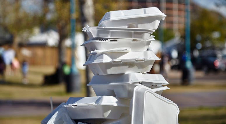 White styrofoam used food containers stacked in trash can in a park Styrofoam Food Containers