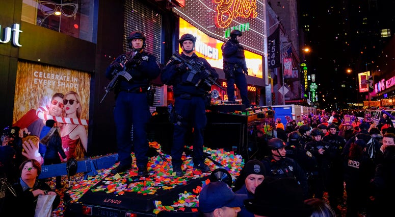 New York Police Officers stand guard as confetti is seen on the air while people take part during New Year's Eve celebrations at Times Square on January 1, 2016 in New York City. NYPD Times Square