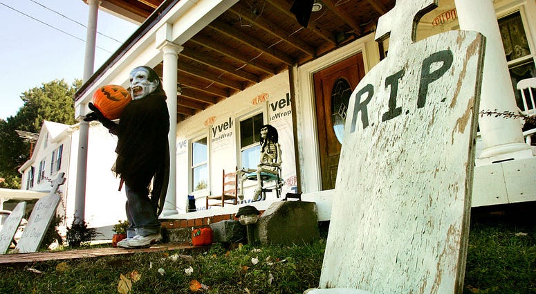 Wearing a mask, Kyndra Hendrick, 6-years-old, helps her parents put out Halloween decorations in front of her house October 17, 2004 in Owings, Maryland. Halloween Decorations