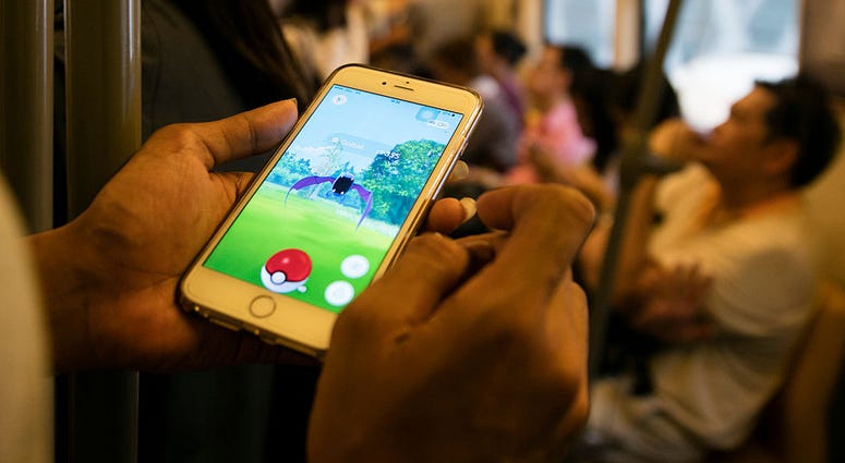 A man plays Pokemon while commuting home from work inside a train in Bangkok, Thailand August 24, 2016. Pokemon Go
