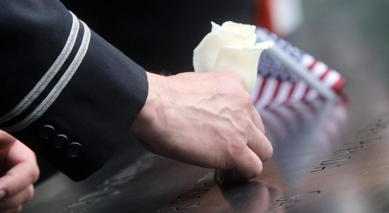 A flight attendant from Long Island, Gregory Davidowitch puts a flower in the name of his friend, Prokopios Paul Zios during ceremonies at the National September 11 Memorial