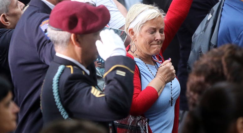 Family and friends of the victims of 911 stand attention during the National Anthem
