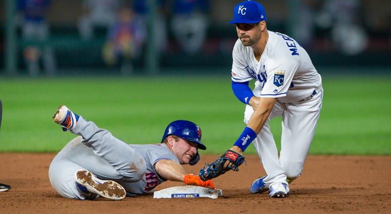 Kansas City Royals second baseman Whit Merrifield (15) misses a throw to second base as New York Mets first baseman Pete Alonso (20) dives to the bag during the ninth inning at Kauffman Stadium. Mets Royals