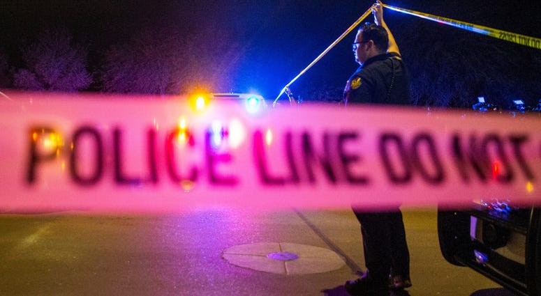 Phoenix Police officer Erik Larson holds up crime tape at a scene where three kids, ages three and under, were found dead at a residence in the 2500 block of E. Vineyard in Phoenix Jan. 20, 2020. Phoenix Police