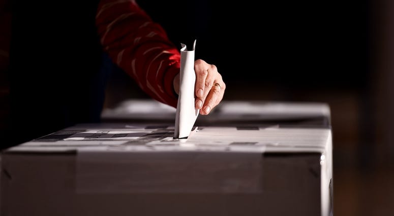 Hand of a person casting a vote into the ballot box during elections Ballot