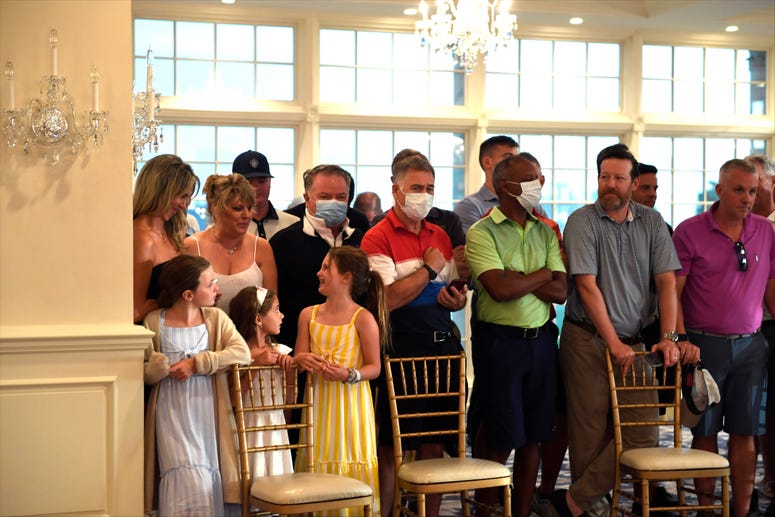 People stand behind chairs as they wait to watch President Donald Trump speak at Trump National Golf Club Bedminster in Bedminster, N.J., Friday, Aug. 7, 2020. Trump NJ