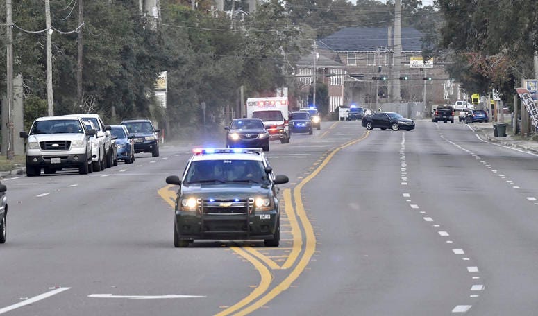 Police cars escort an ambulance after a shooter open fire inside the Pensacola Air Base, Friday, Dec. 6, 2019 in Pensacola, Fla. Florida air naval base shooting