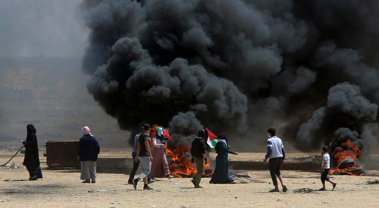 Palestinian protesters burn tires near the Israeli border fence, east of Khan Younis, in the Gaza Strip, Monday, May 14, 2018. Gaza Protests