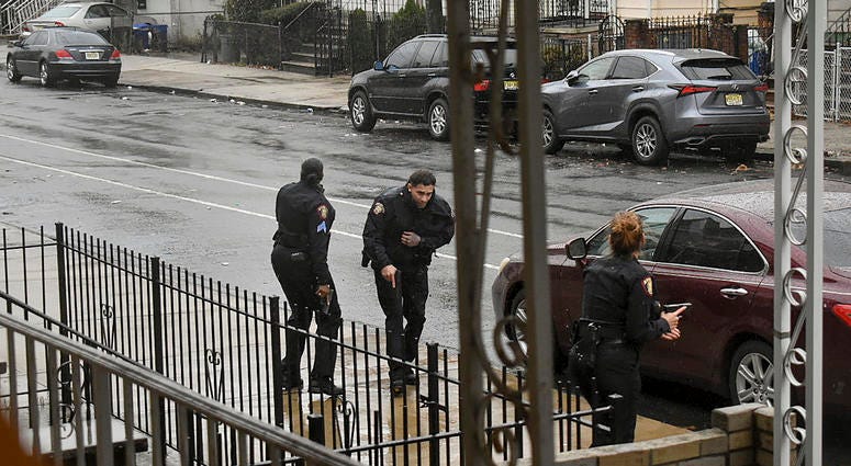 In this Dec. 10, 2019 photo, Jersey City police Sgt. Marjorie Jordan, left, helps fellow officer Raymond Sanchez to safety after he was shot during a gunfight that left multiple dead in Jersey City, N.J. Jersey City shooting