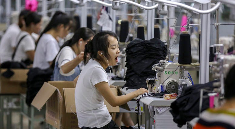 In this Thursday, Aug. 2, 2018, photo, a woman yawns at a factory making swimming suits in Jinjiang city in southeast China's Fujian province. China Factory
