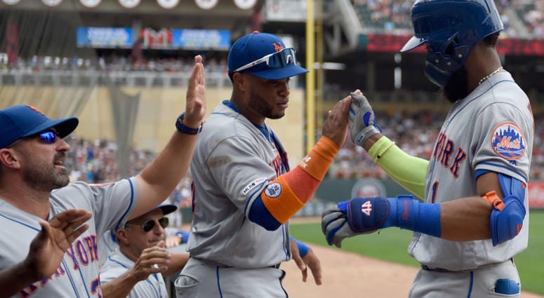 manager Mickey Callaway #36 and Robinson Cano #24 of the New York Mets congratulate Amed Rosario #1 on a solo home run against the Minnesota Twins during the third inning of the interleague game on July 17, 2019 Mets v Twins