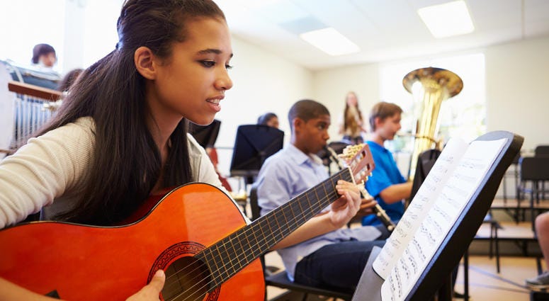 Students learn how to play instruments in a music class. High School Music Class