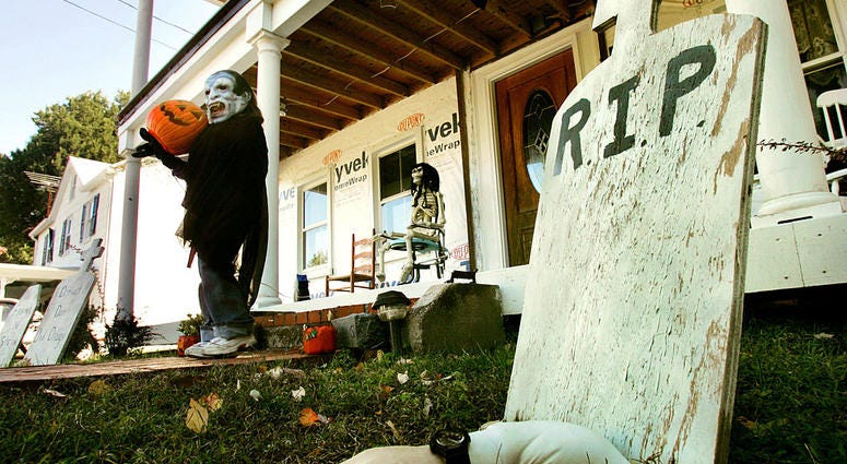 Wearing a mask, Kyndra Hendrick, 6-years-old, helps her parents put out Halloween decorations in front of her house October 17, 2004 in Owings, Maryland. Halloween Decorations